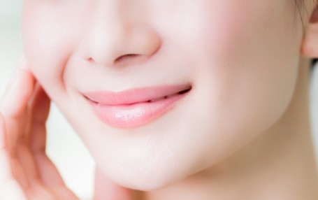 Close-up of a person's lower face smiling, with a hand resting on the cheek.